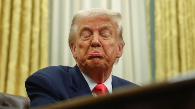 US president Donald Trump pulling a face at a desk.