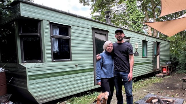 Rudi and Lauren Smith outside their green static caravan, with their dog